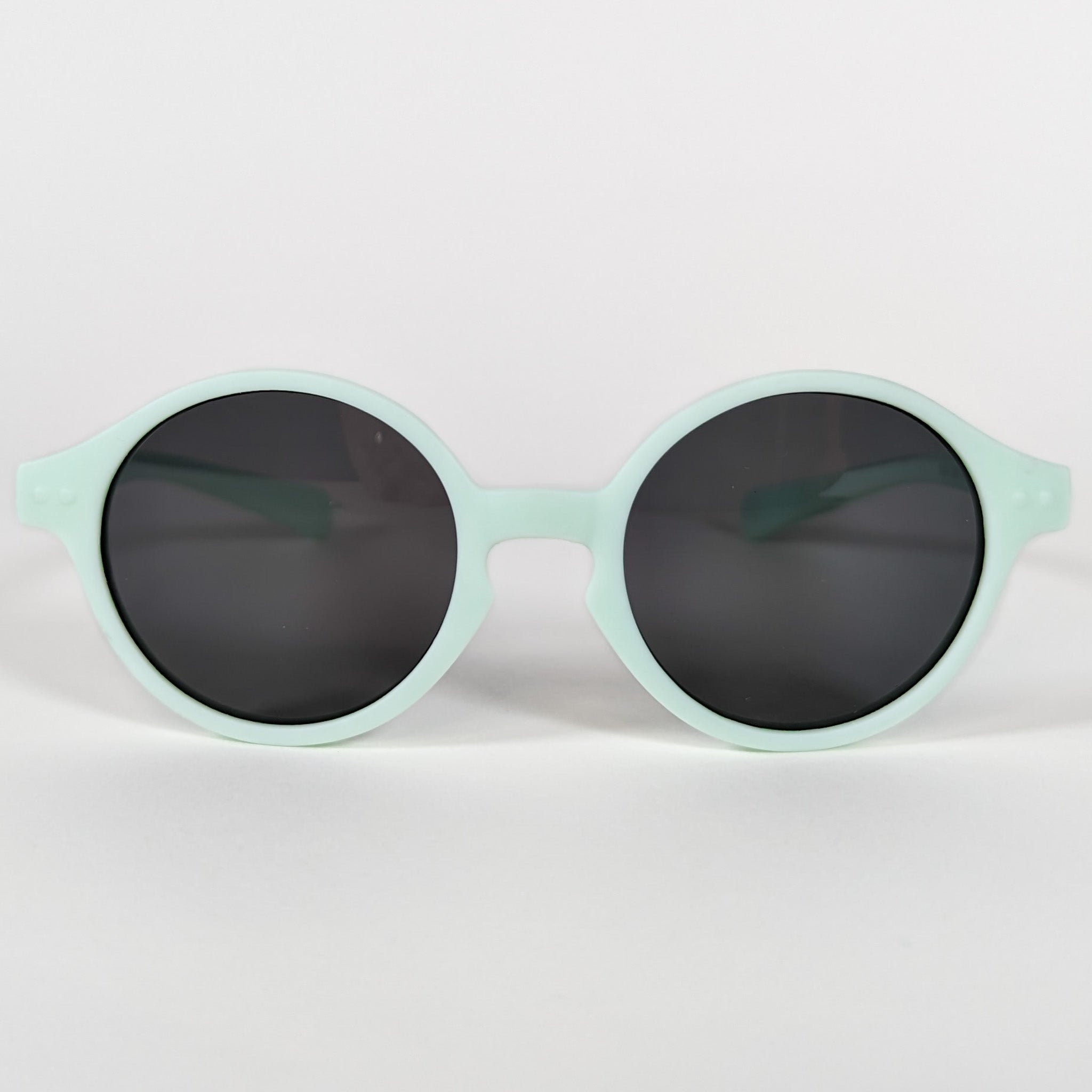 Zoomed in view of baby sunglasses with a mint green frame and round lenses.