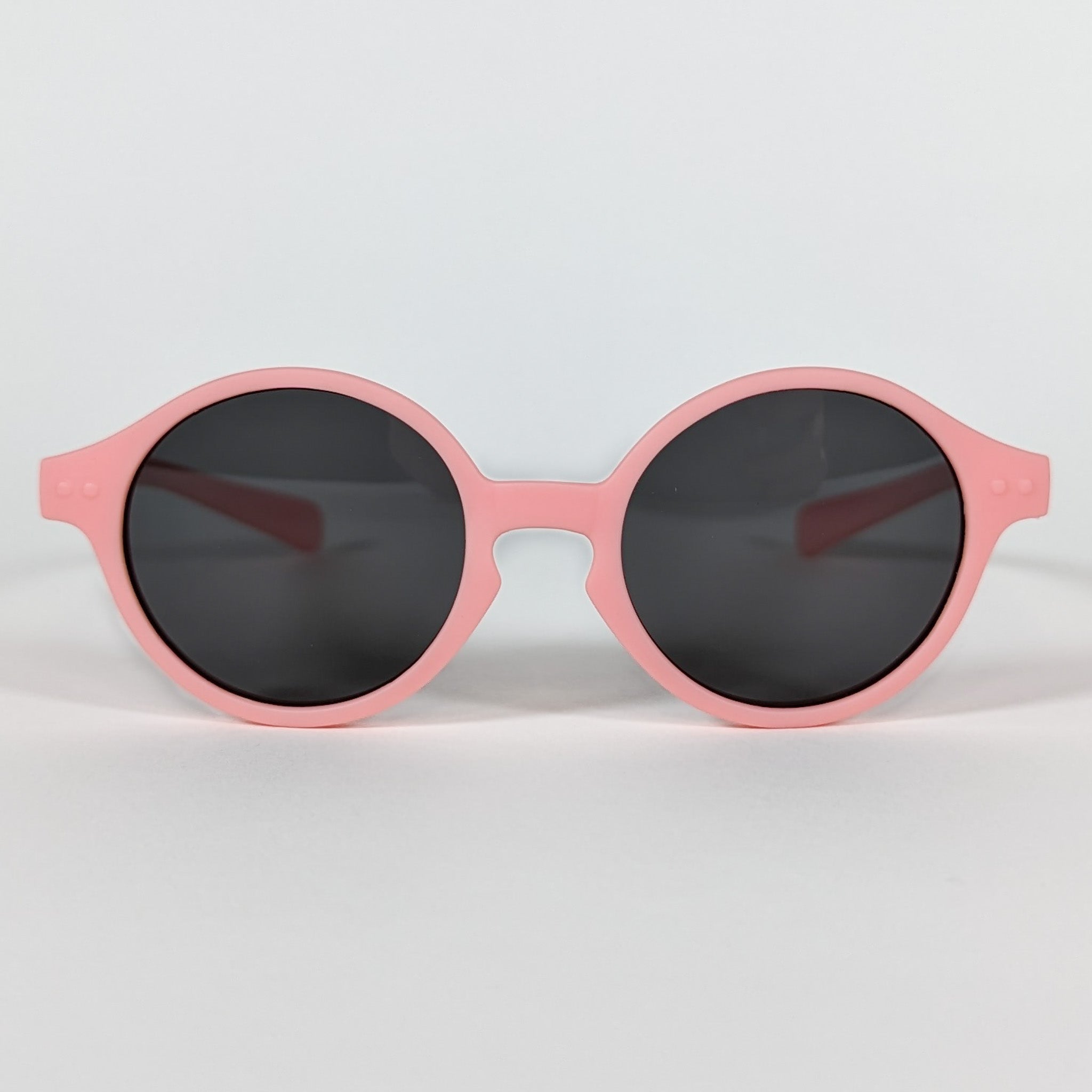 Zoomed in view of baby sunglasses with an pink frame and round lenses.