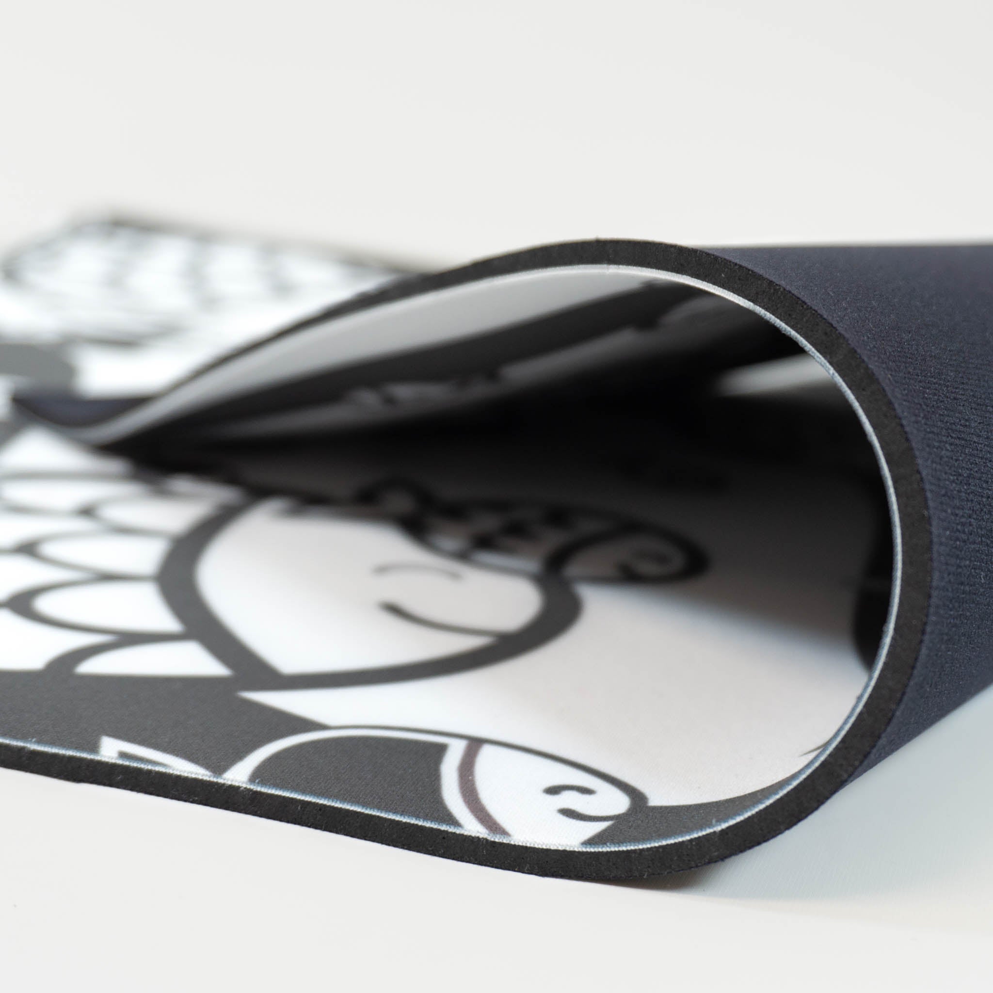 A newborn tummy time mat folded over, with a black and white print of a school of fish.