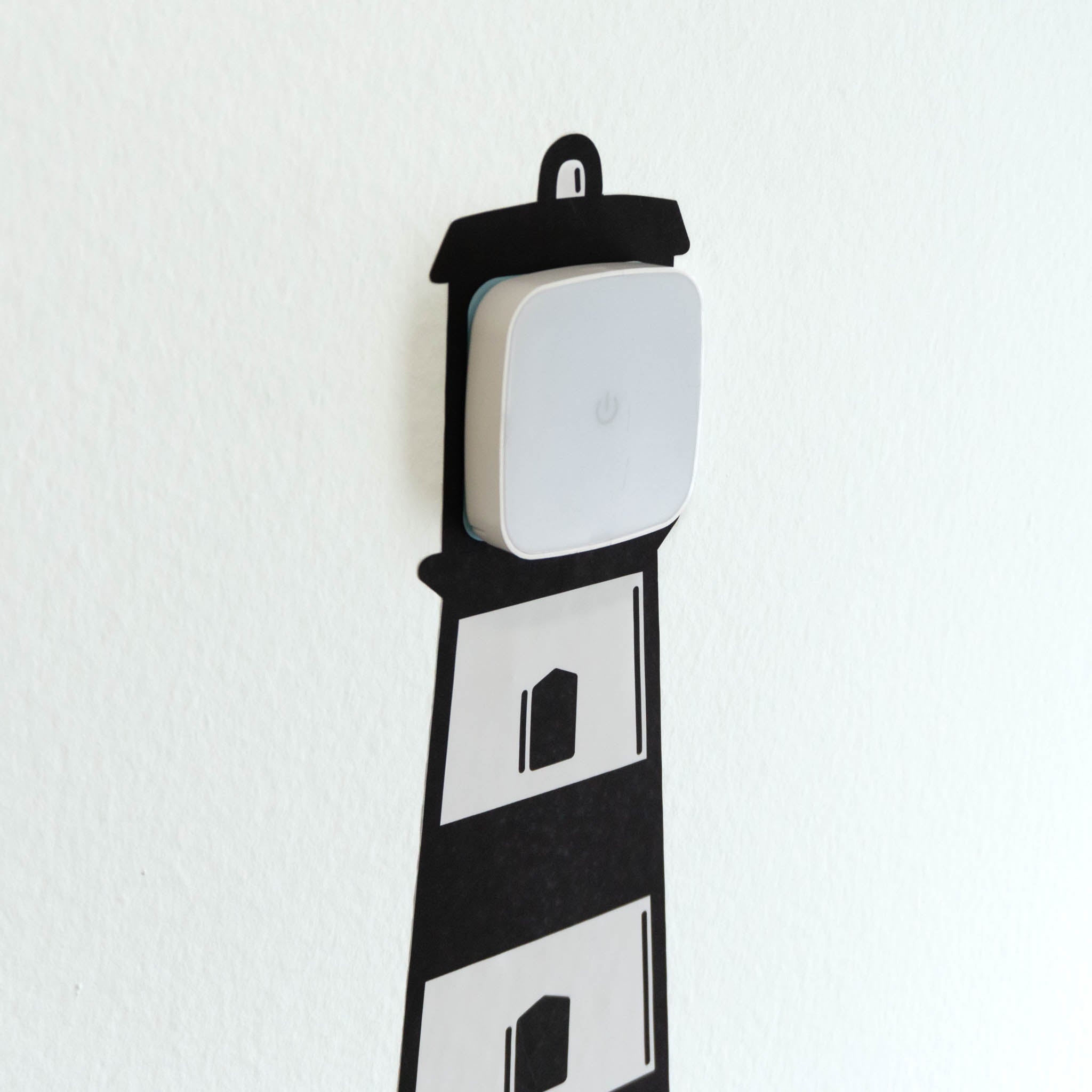 A touch activated night light mounted on a wall decal of a lighthouse.