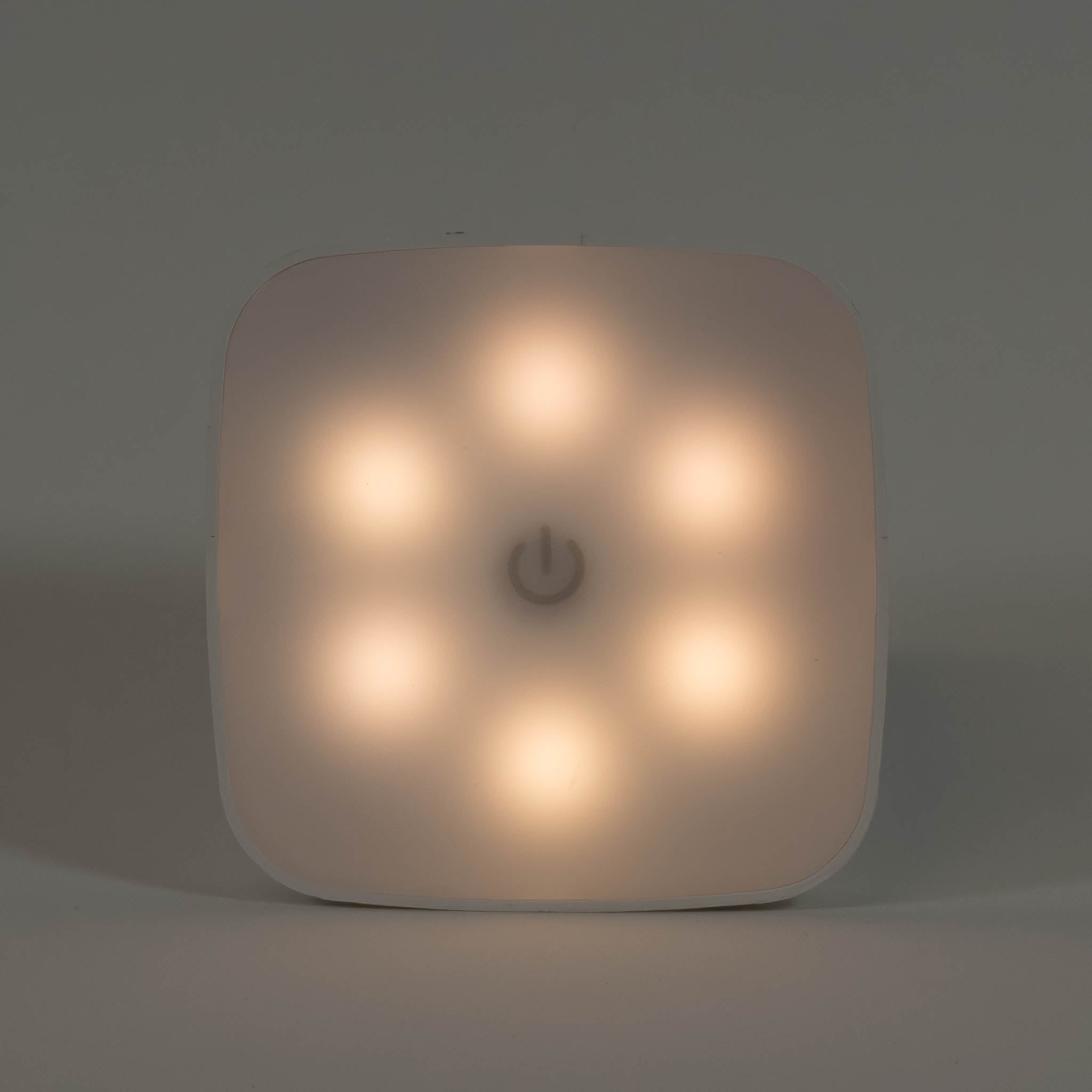 A zoomed in photo of a square night light showing a warm white hue.