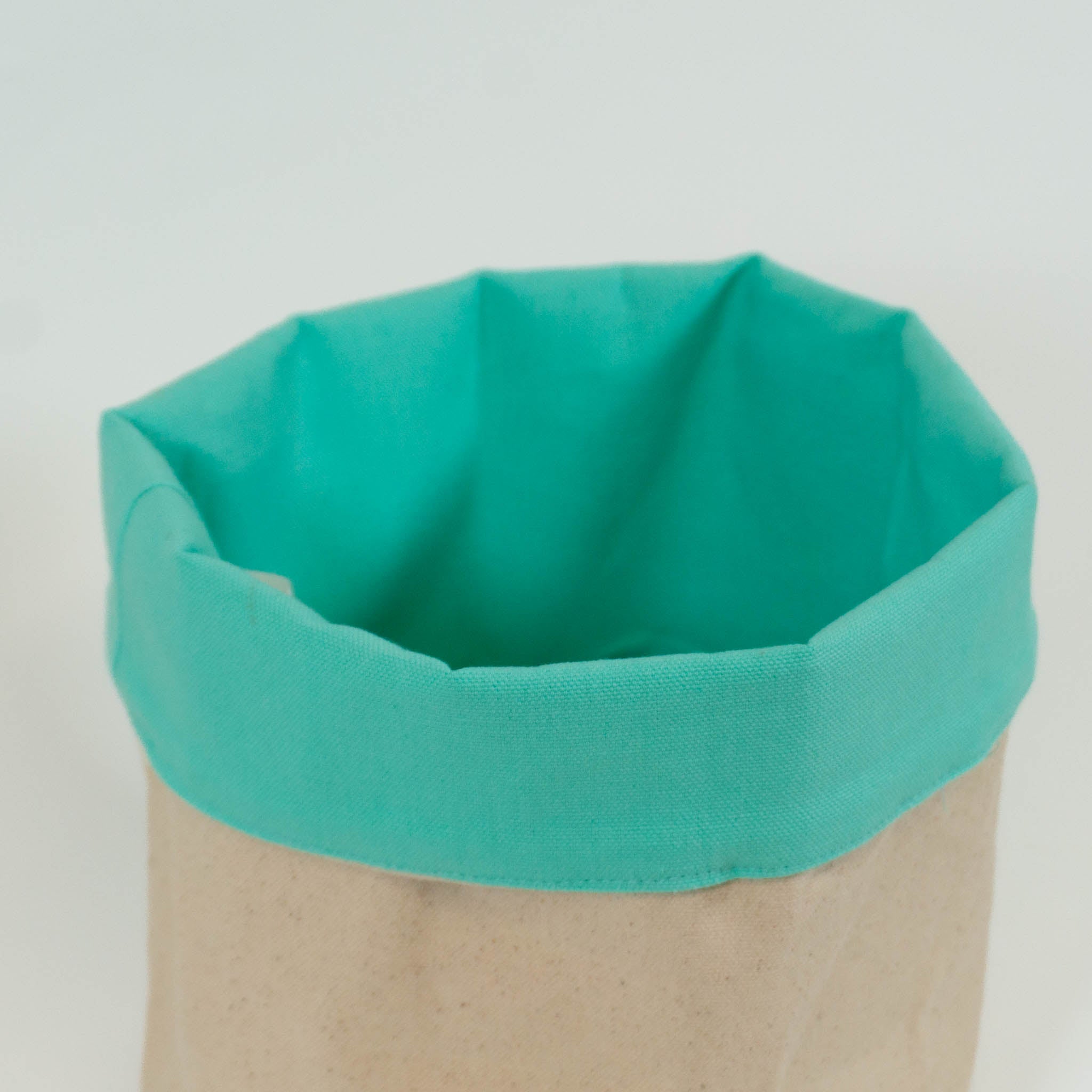 A cloth storage basket with a mint green inside and beige outside. 