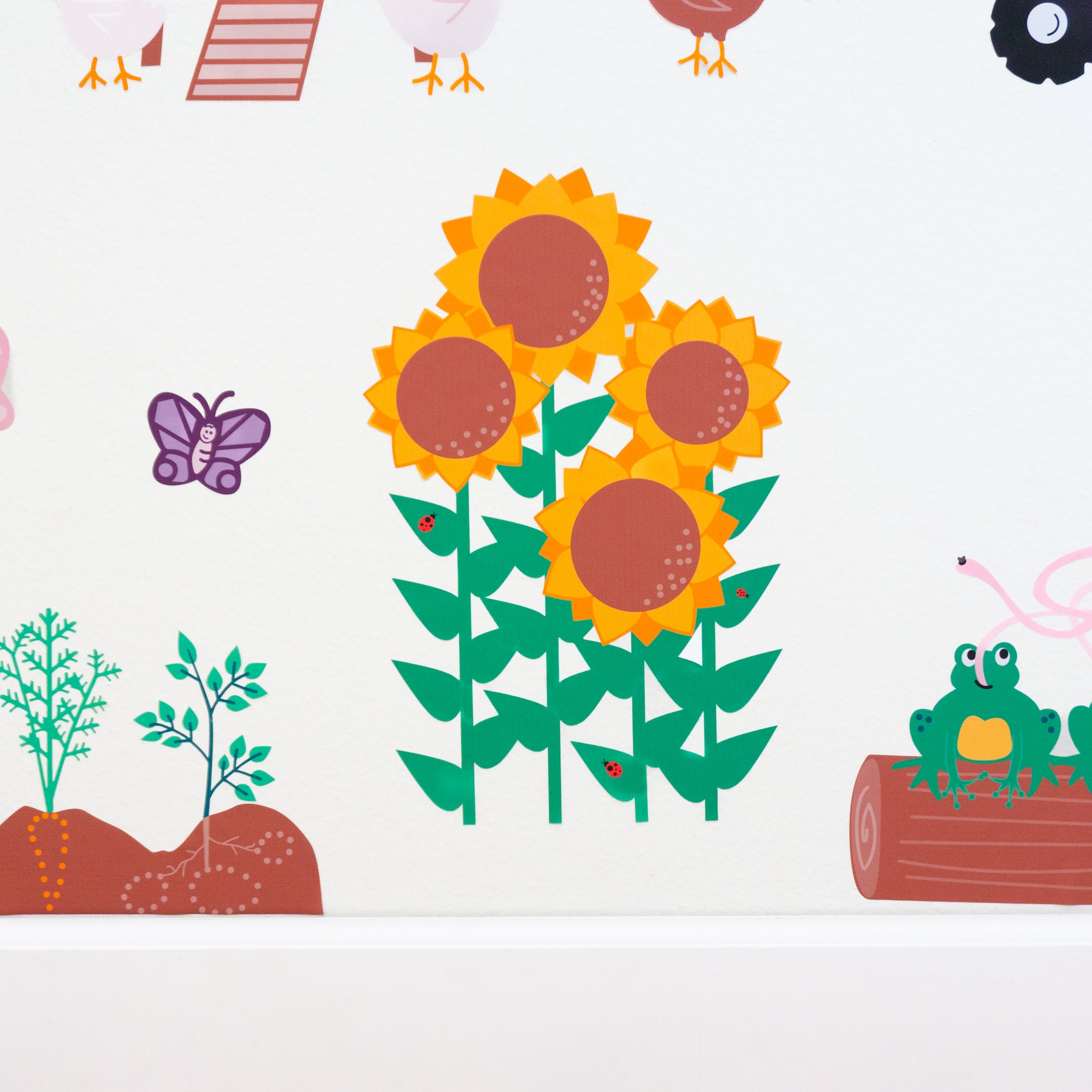 A close up of a wall decal of 4 yellow and brown sunflowers, with green stems and 3 lady bugs on random leaves on a white wall.