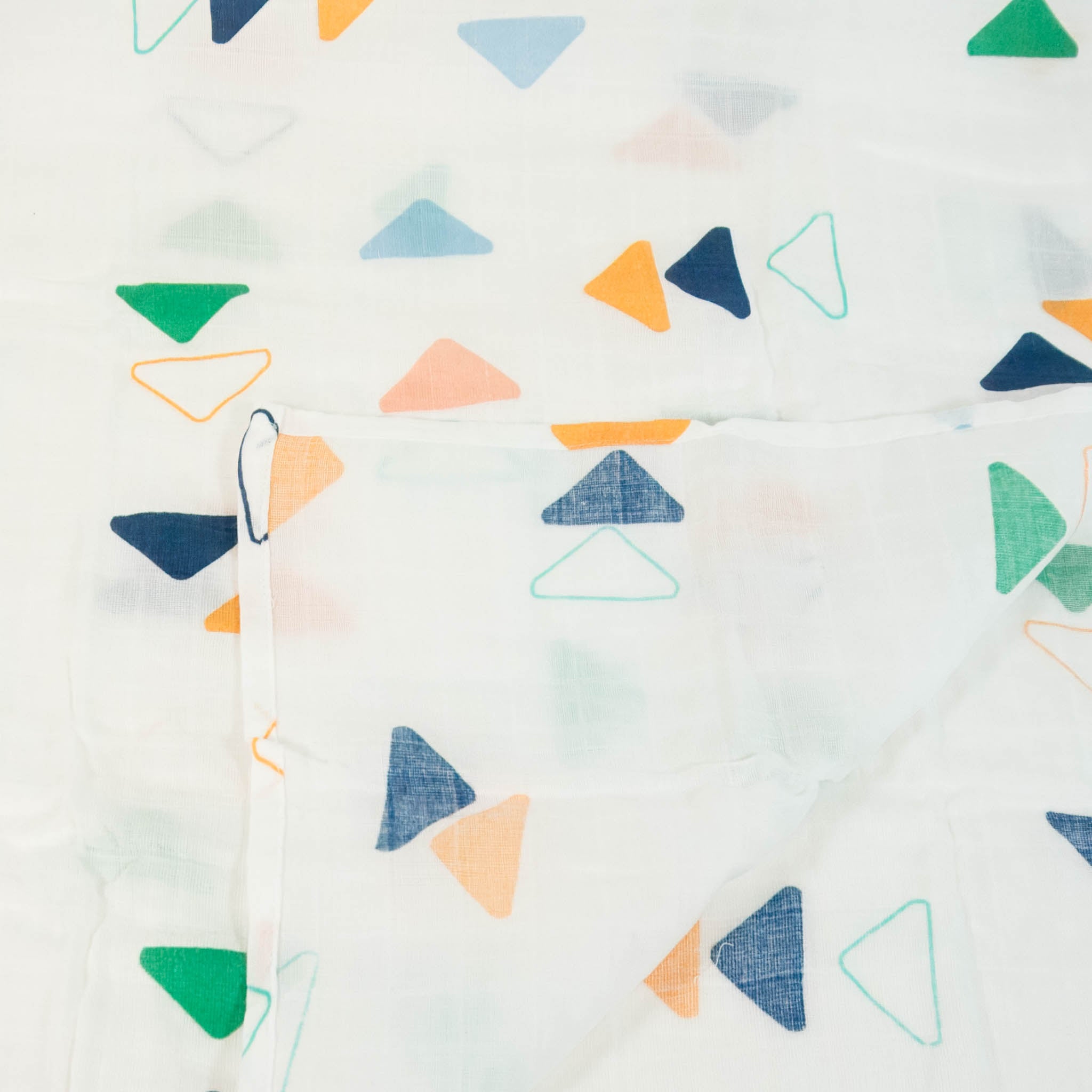 A closeup of a muslin blanket with a multicolored triangle pattern.