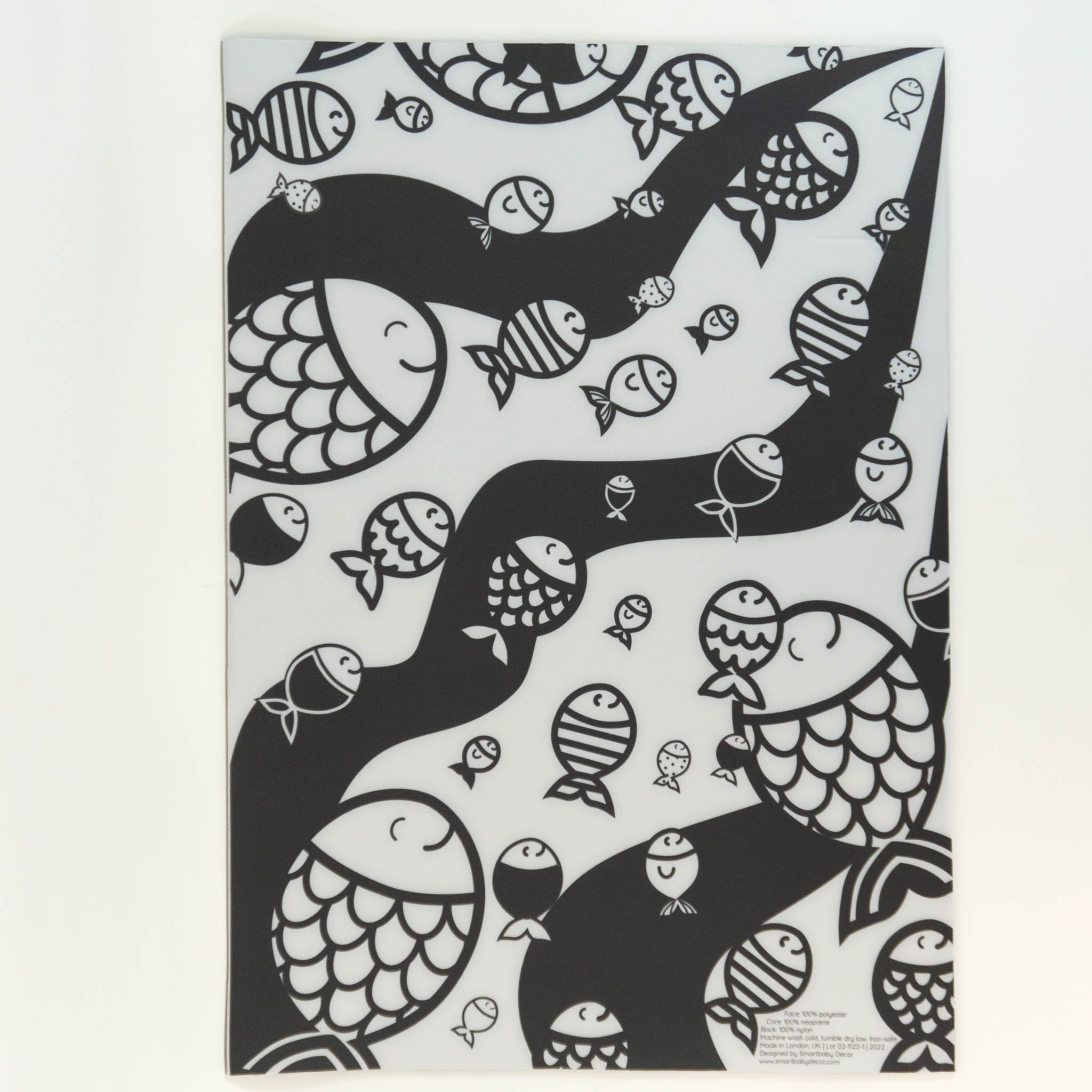 A picture of a newborn tummy time mat which is black and white with a cartoon depiction of a school of fishes swimming in waves.