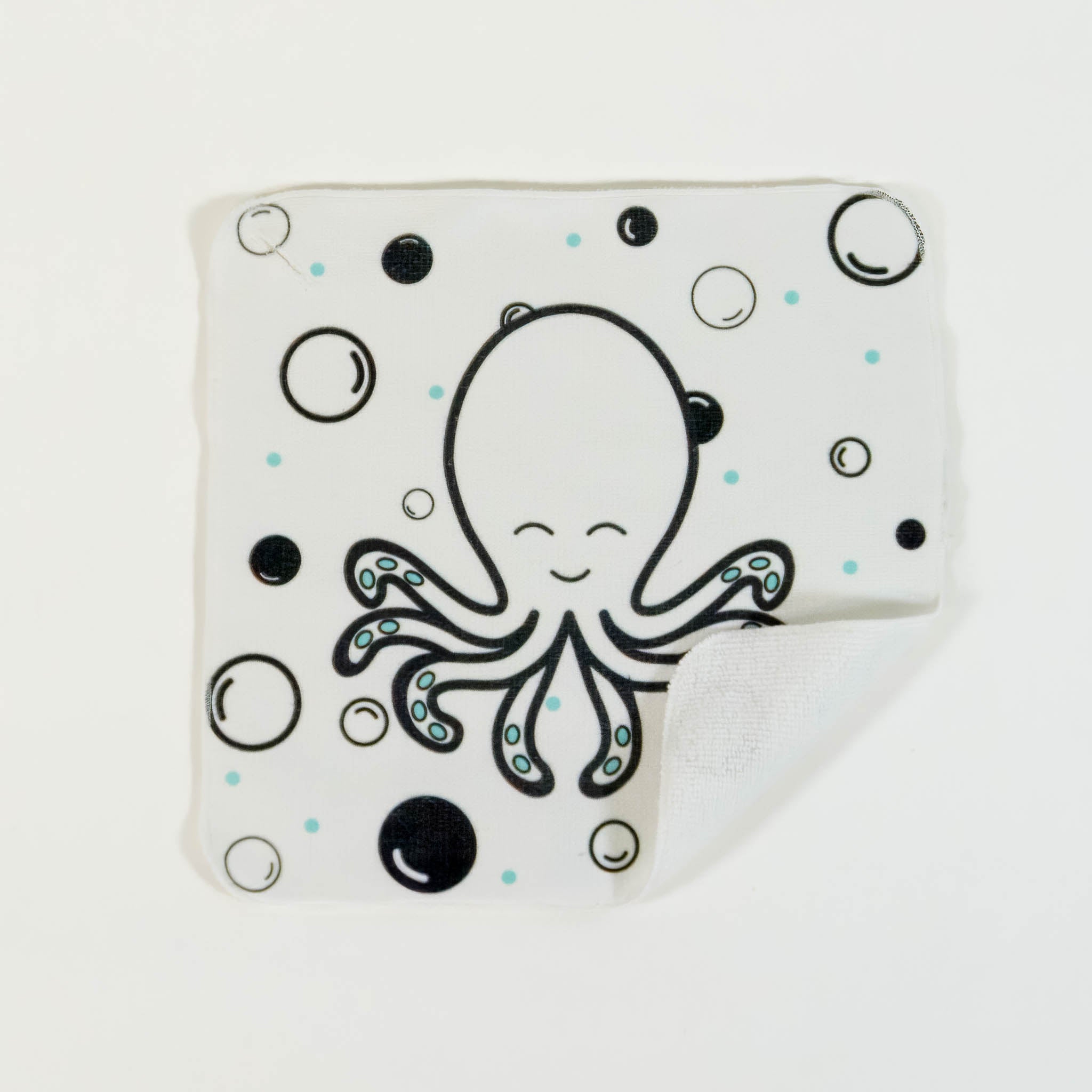 A close up of a white washcloth for babies, with a black and white pattern of an octopus and bubbles.