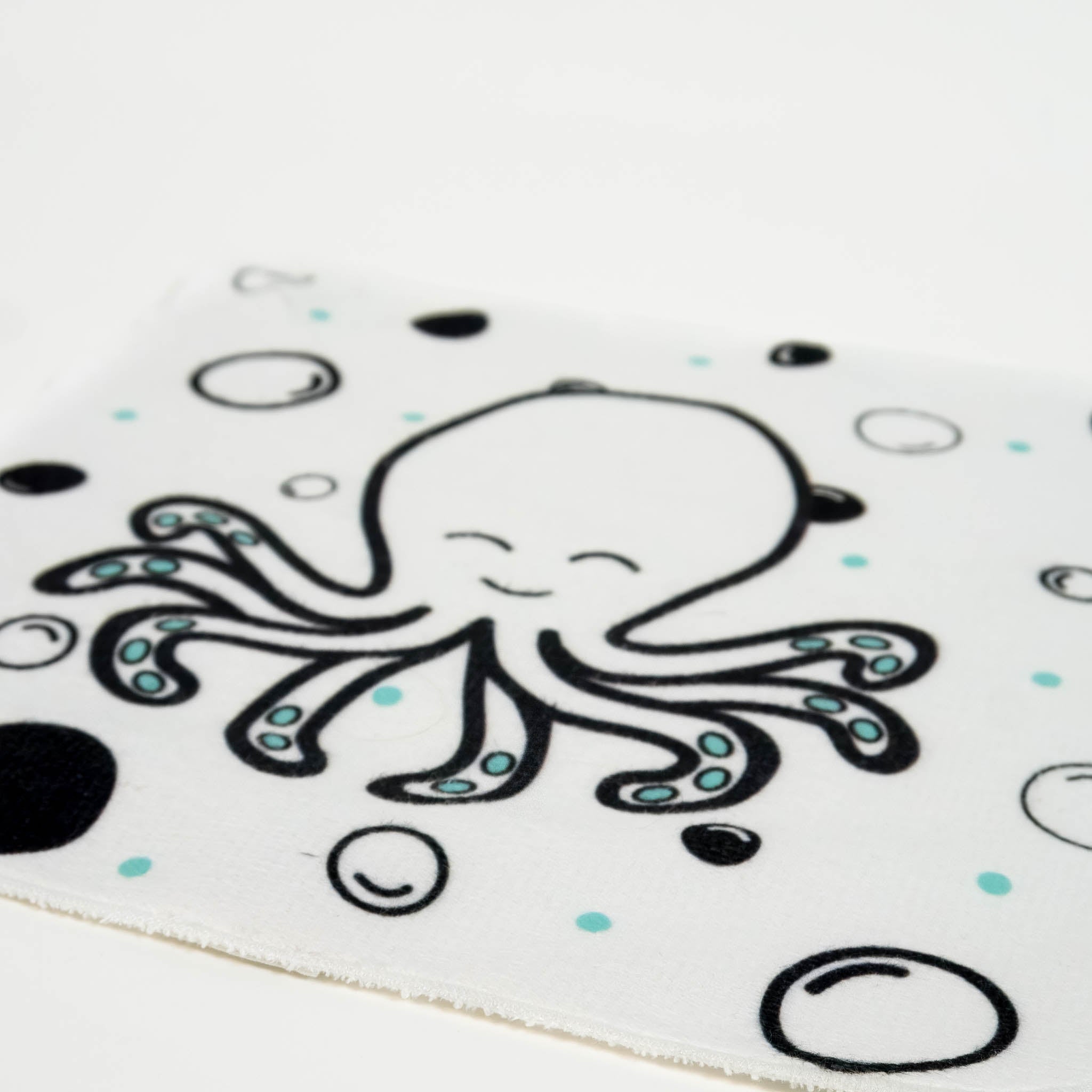 A close up of a white washcloth for babies, with a black and white pattern of an octopus and bubbles.