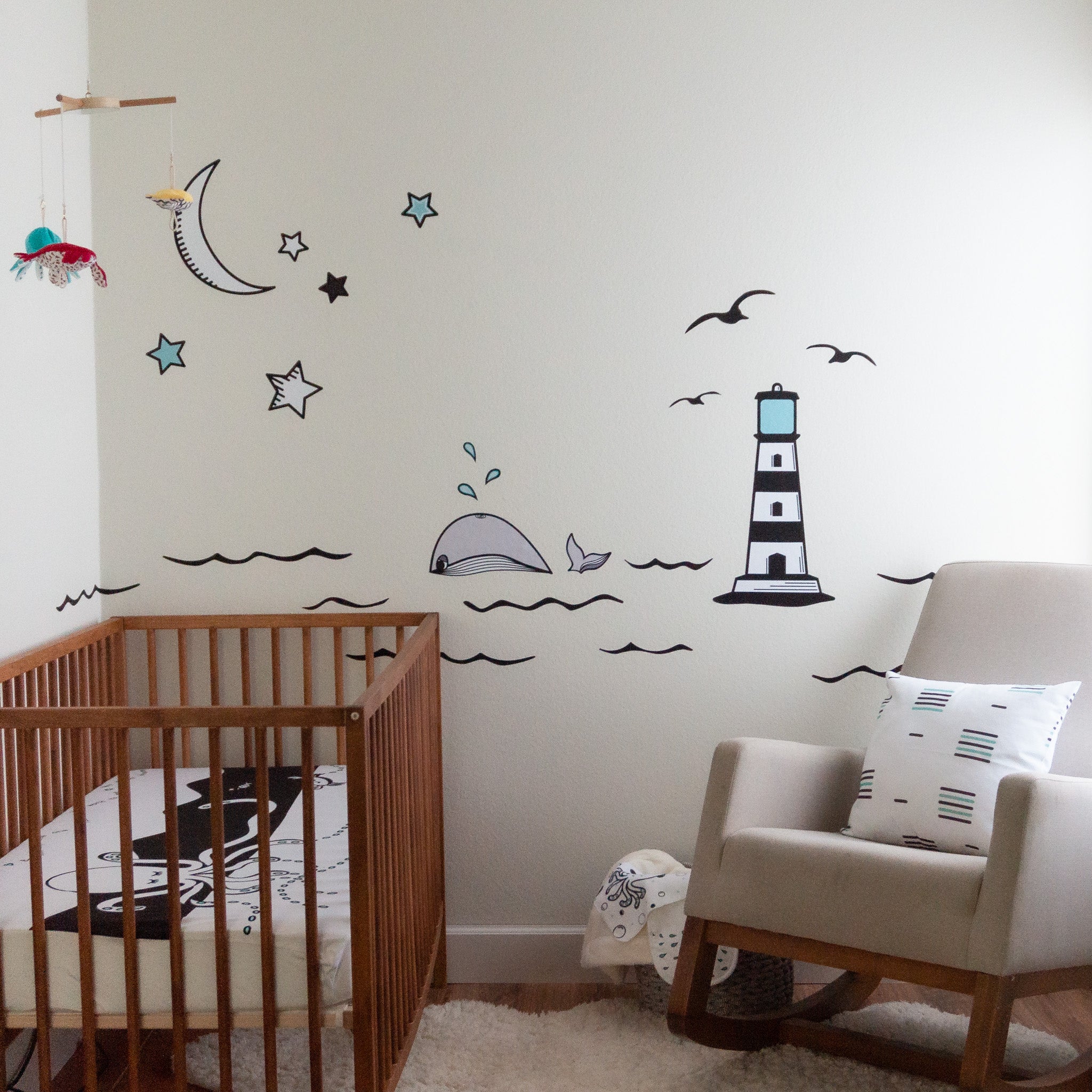 A nursery scene with an ocean mural on the wall, a rocking chair and crib in a high contrast theme.