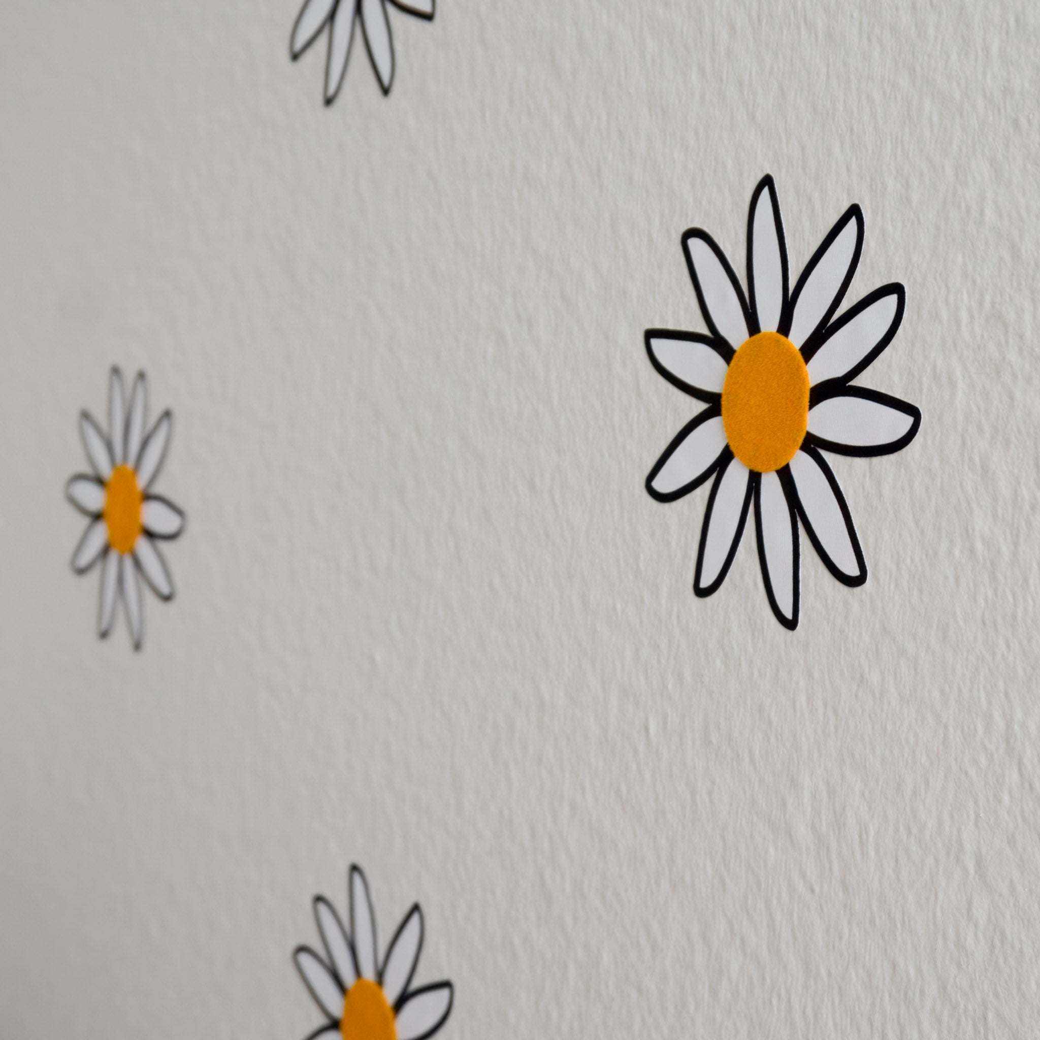 Side view of wall with scattered daisy wall decals with velvet, tactile, yellow centers