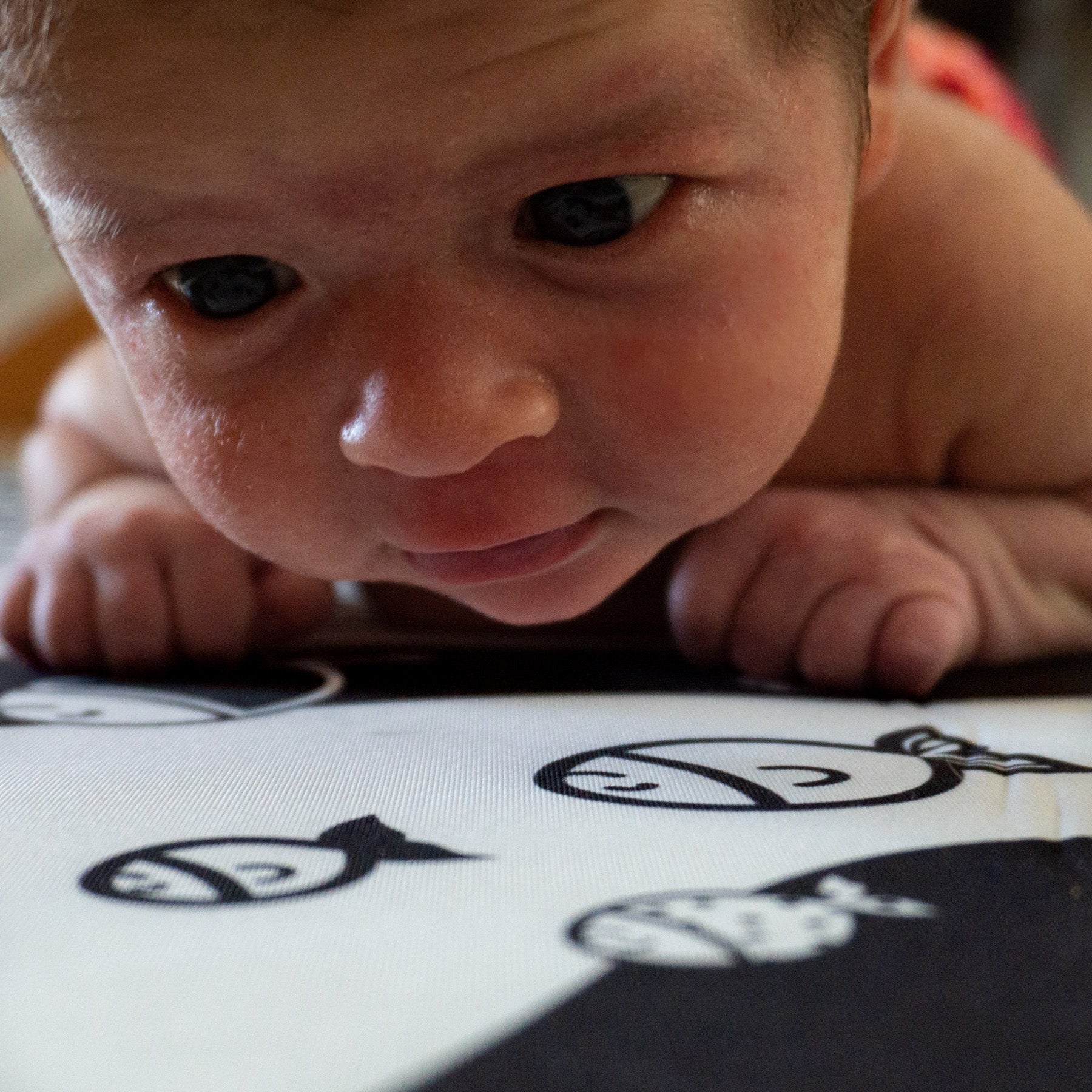 A newborn baby looking at a fish pattern in black and whtie.