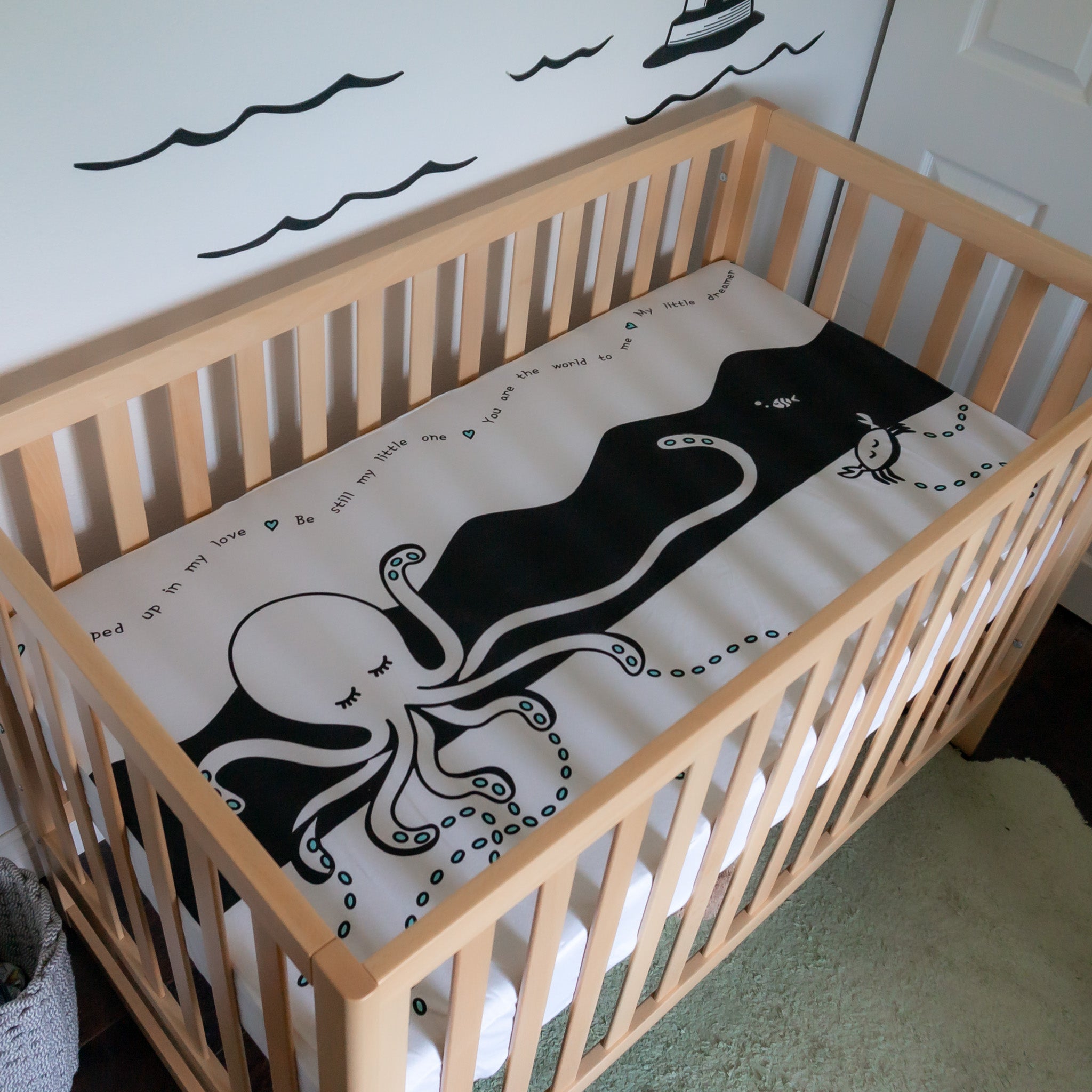 A crib with a black and white crib sheet of an octopus on it.