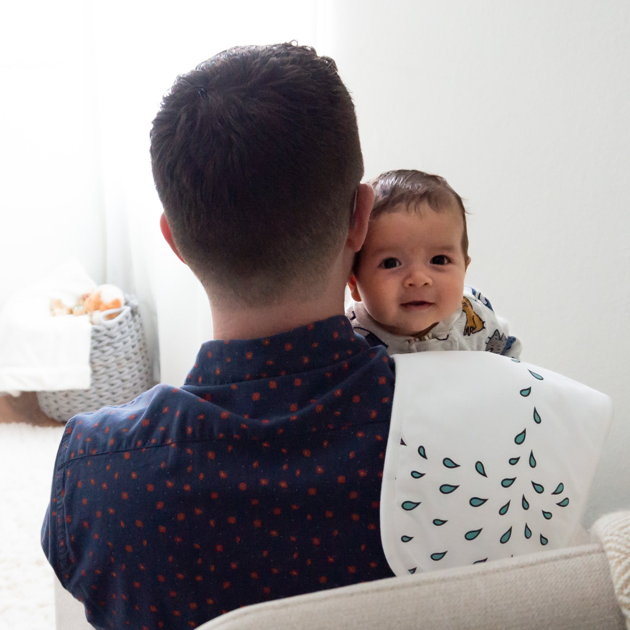 A baby being held by his father with a burp cloth draped over his shoulder. 